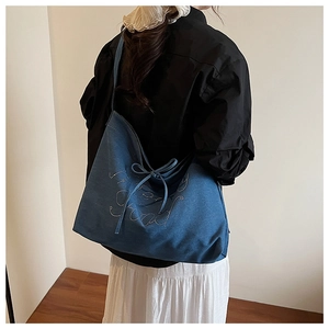 Detail of navy blue large tote bag with denim texture, bow ribbon, and sparkling crystals