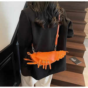 Detail of creative orange lobster shaped shoulder bag with rivet accents on a model