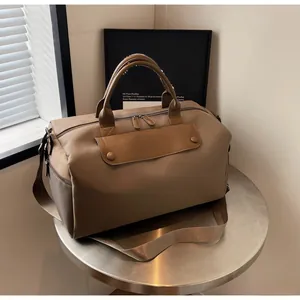 Close-up of large khaki fitness travel bag with leather accents on a round metal table