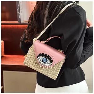 Close-up of woven straw bag with pink leather flap and beaded evil eye detail