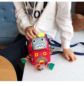 Détail d'un sac bandoulière enfant rouge en forme de robot avec des accents colorés en toile