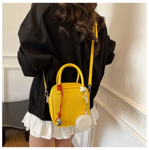 Detail of yellow pebbled leather crossbody bag with red woven cord and white coin purse