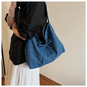Detail of blue denim tote bag with sparkling crystal letters and chic bow decoration
