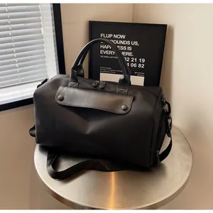 Close-up of black oxford fabric travel bag with leather accents on a metal table