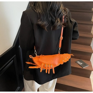 Detail of creative orange lobster-shaped crossbody bag with fringe legs and slim strap