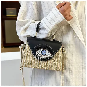 Close-up of woven straw bag with evil eye embroidery and decorative beads details