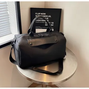 Close-up of black oxford travel bag with metallic buckles and adjustable shoulder strap