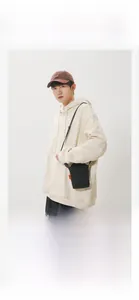 Detailed view of a black minimalist crossbody phone bag with an orange brand tag detail