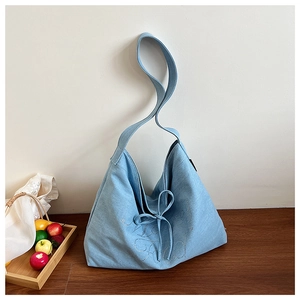 Light blue denim tote bag detail featuring rhinestone script and a drawstring bow tie