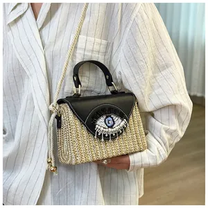 Detail of evil eye bead embroidery and pearl accents on beige straw woven bag