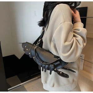 Detail of lobster-shaped crossbody bag featuring black faux leather and gold rivets