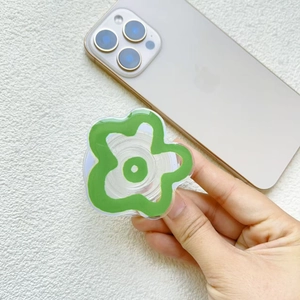 Close-up of a green flower-shaped acrylic phone grip with a white folding base on a phone
