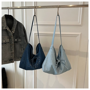 Detail of denim tote bags with rhinestone lettering and bow tie decor in two blue shades