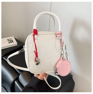 Close-up of white lychee leather square handbag with mini pink pouch and red cord detail