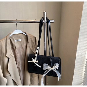 Dettaglio borsa a spalla nera rettangolare con trama effetto legno e fiocco in organza