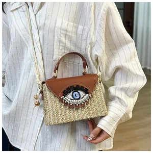 Detail of straw crossbody bag with embroidered evil eye beadwork and sequin tassels