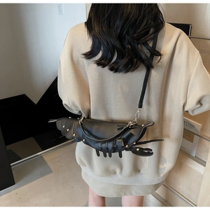 Detail of creative black lobster shaped crossbody bag with gold studs on a model
