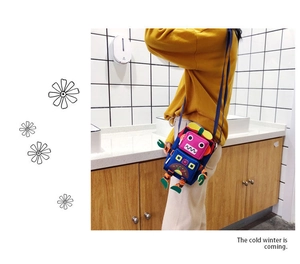 Détail d'un sac bandoulière coloré en forme de robot avec éléments mécaniques
