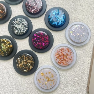 Detail of colorful gold foil and glitter resin MagSafe phone grips on white fabric