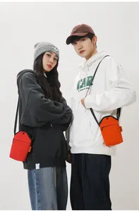 Detail of red and orange canvas crossbody phone bags with front zipper and side label
