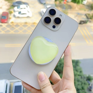 Detail of a translucent heart-shaped MagSafe phone grip in jelly green on a smartphone