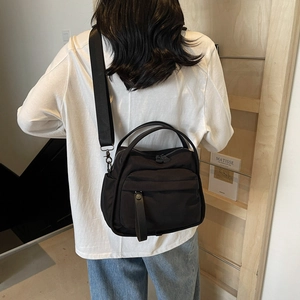 Black lightweight nylon crossbody tote bag with dual straps worn by a female model