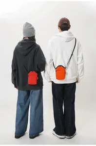 Detail of red and orange canvas shoulder bags worn as crossbody phone pouches on models