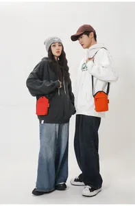Close-up of red and orange mini canvas crossbody bags worn by models for street style