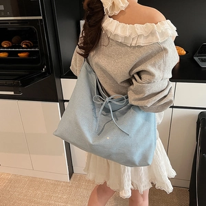 Large blue denim tote bag with rhinestone letter decor and bow shown on a model