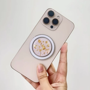 Detail of a pink MagSafe phone socket with gold leaf flakes and magnetic ring held by hand