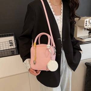 Pink lychee leather mini crossbody bag with charm accessory shown on a model