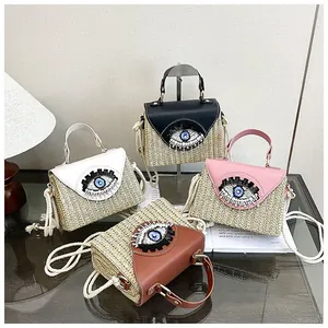 Close-up of bohemian straw mini bags featuring embroidered eyes and corded strap