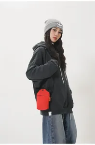 Close-up of a mini red canvas neck pouch paired with a gray hoodie and blue jeans