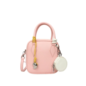 Pink lychee textured crossbody bag with yellow handle wrap and mini heart charm detail