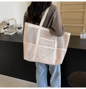 Detailed view of beige mesh tote bag with white webbing handles on model in a cafe setting