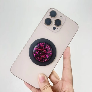 Detail view of round MagSafe phone stand with purple gold foil and resin drips on iPhone
