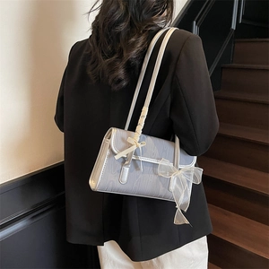 Borsa a tracolla azzurra con trama in legno e fiocchi in tulle su una modella alla moda