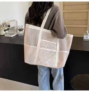 Spacious mesh tote bag in beige shown worn on shoulder in a cozy cafe setting