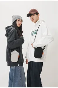 Detail of minimalist canvas crossbody phone bags in cream and black with zip closure