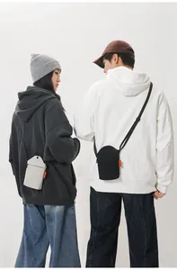 Detail of minimalist canvas mini crossbody phone bags in black and beige with orange tags