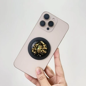 Detail of a handmade MagSafe phone grip with gold foil and green resin art on an iPhone