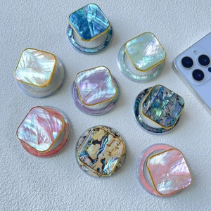 Flat lay of colorful shell pattern magnetic phone grips with gold borders on white background