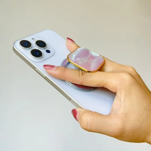 Close-up of pink shell phone stand with gold metal frame on a white smartphone