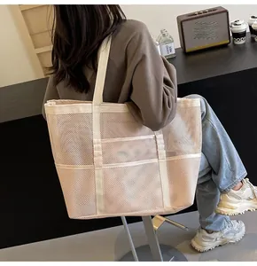 Detail view of large mesh tote bag with three front pockets and woven shoulder straps