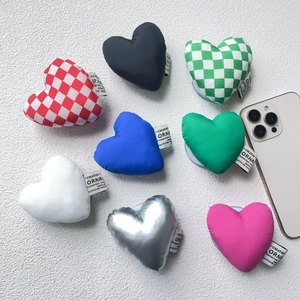 Detail view of heart-shaped plush magnetic phone grips in colorful checkered patterns