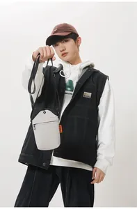 Detail of grey mini canvas crossbody bag showing orange brand label and black zipper pocket