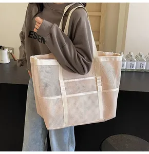 Close-up of a large beige mesh tote bag with wide shoulder straps for beach and gym