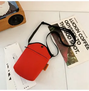 Detail of red canvas mini messenger bag with metal snap button and adjustable strap
