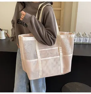 Close-up of a large beige mesh tote bag with reinforced canvas straps for beach use