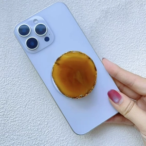 Détail macro du support de téléphone en agate avec bord doré sur smartphone bleu